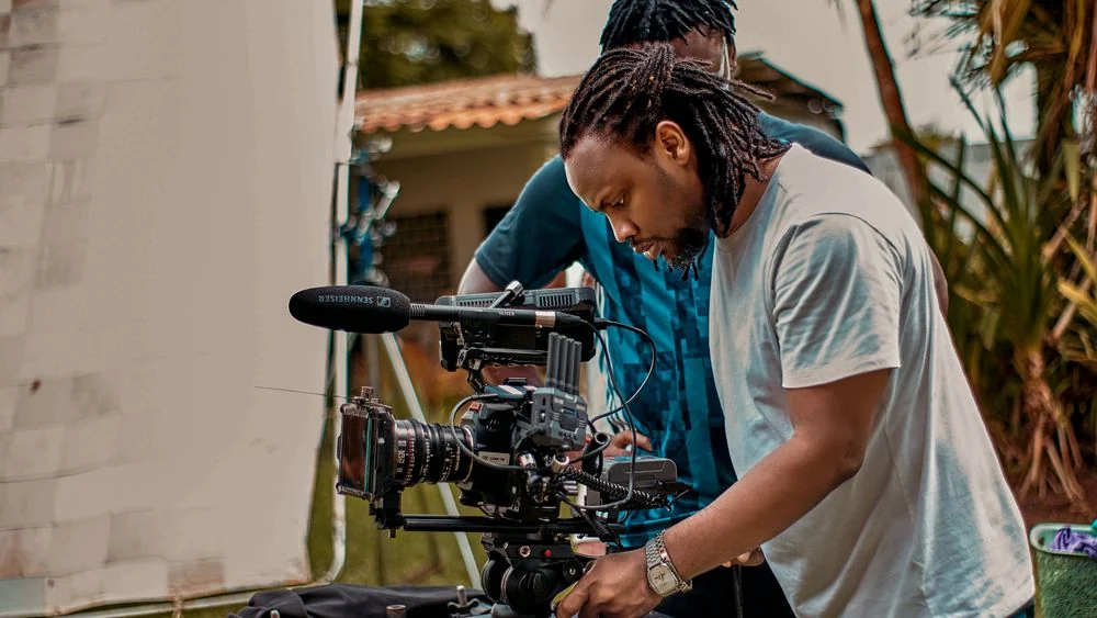 Mory prépare une caméra de cinéma sur un tournage en extérieur.